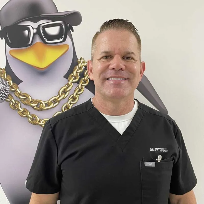 Foto del Dr.. Frank Pettinato II con un pingüino detrás de él