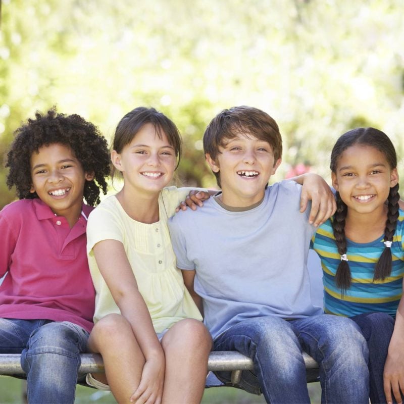 Four kids sitting together and smiling